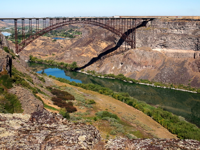 [The entire arch of the bridge is in view as it spans the canyon. the arch supports on either side only go about halfway down the canyon wall.]